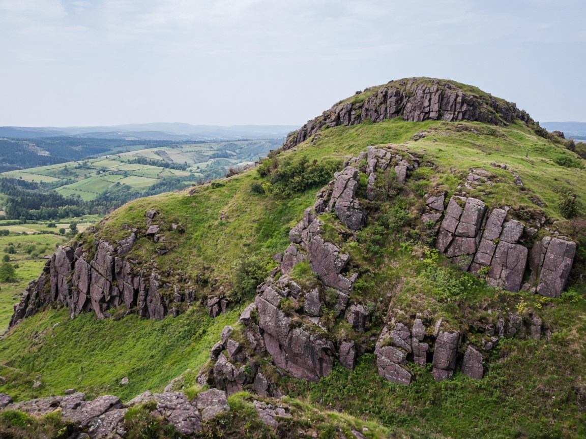 Dunkler Basalt auf einem grasbewachsenen Hügel der Rhön mit Blick zur Milseburg